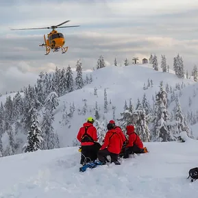 a helicopter approaching an alpine rescue team